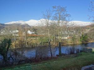 a river with snow covered mountains in the background at 10 Elm Court in Keswick