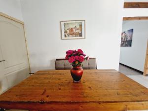 wazon kwiatów siedzący na drewnianym stole w obiekcie Confort INN w mieście Otopeni