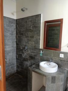 uma casa de banho com um lavatório e uma parede de tijolos em Diary home stay em Ubud