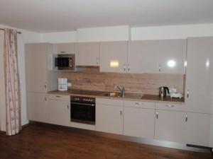 a kitchen with white cabinets and a sink at Landhaus Alpenjäger in Hainzenberg