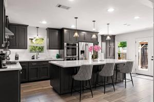 a kitchen with black cabinets and a kitchen island with stools at Stunning Pool and Chefs Kitchen NRG MedCenter in Houston