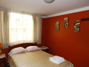 1 dormitorio con paredes rojas y 1 cama con 2 almohadas en El Álamo, en Arequipa