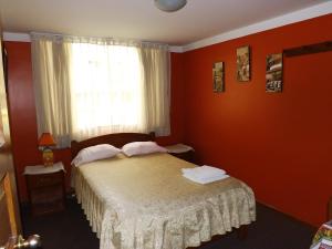 Un dormitorio con una cama con paredes rojas y una ventana en El Álamo, en Arequipa