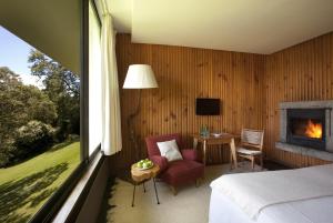 um quarto com uma cama, uma lareira e uma mesa em Hotel Antumalal em Pucón