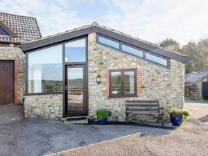 a stone house with glass doors and a bench at Old Orchard Barn - The Annexe in Buckland St Mary