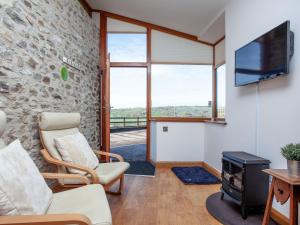 a living room with a tv and a stone wall at Old Orchard Barn - The Annexe in Buckland St Mary