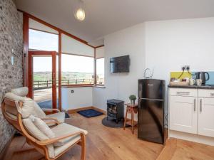 a kitchen with a refrigerator and a chair and a stove at Old Orchard Barn - The Annexe in Buckland St Mary