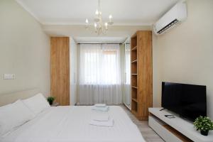 um quarto com uma grande cama branca e uma televisão em Studio in the center em Almaty