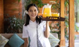 a woman holding a tray of orange juice at Villa Little Mannao in Kerobokan
