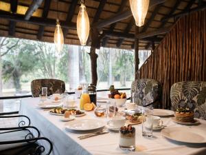 a long table with plates of food on it at Kruger Eden Lodge in Marloth Park