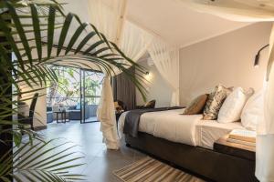 a bedroom with a bed and a large plant at Kruger Eden Lodge in Marloth Park