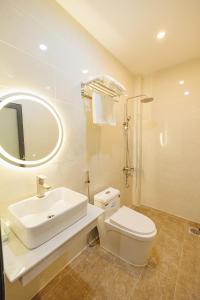 La salle de bains est pourvue d'un lavabo, de toilettes et d'un miroir. dans l'établissement Happy Hotel, à Bạc Liêu
