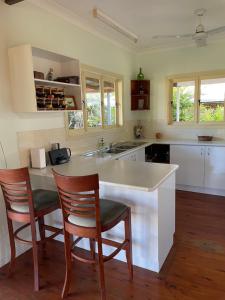 a kitchen with a white counter and two chairs at Seafarer Cottage in South Mission Beach