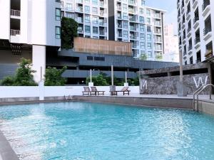 une piscine avec deux bancs et des bâtiments dans l'établissement Watana Hotel, à Bangkok