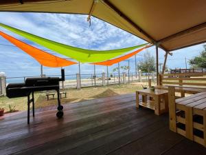 a hammock on a deck with the beach in the background at Rembulan Escape - Beachfront safari tent in Penarek