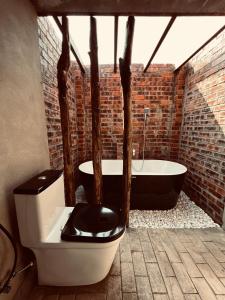 a bathroom with a toilet and a bath tub at Rembulan Escape - Beachfront safari tent in Kampung Penarik