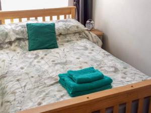 a bed with two green towels on it at Pankhurst in Louth