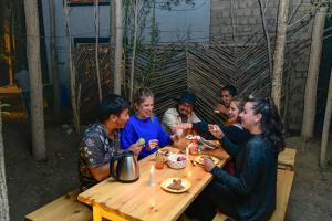 un gruppo di persone sedute a un tavolo che mangiano cibo di Raybo Hostel - Serene stay with 5 mins walk from the main market a Leh