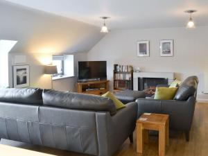 a living room with a leather couch and a tv at Alnwick Old Brewery Apartment in Alnwick