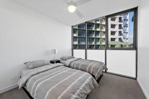 two beds in a bedroom with a window at Lovely 2 Bedroom unit Pool,Gym workspace & more in Brisbane