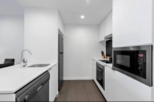 a white kitchen with a sink and a microwave at Lovely 2 Bedroom unit Pool,Gym workspace & more in Brisbane
