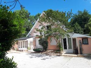 a pink and white house with trees in front of it at Ravissant T2 terrasse privative et parking in Odos