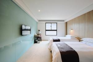 ein Hotelzimmer mit zwei Betten und einem Schreibtisch in der Unterkunft GOGO Hotel City Hall in Taichung