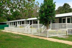 a white picket fence in front of a house at Sahara Trails Cabin 2 WiFi Air Conditioning Horse Riding and much more in Anna Bay +12 photos