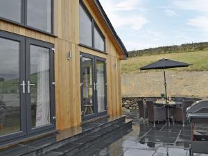 a house with a patio with a table and an umbrella at Sprint Lodge in Burneside