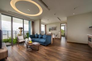 een woonkamer met een blauwe bank en een tafel bij Flamingo Premium Lan Ha Bay Resort in Hai Phong