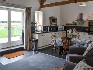 a living room with a table and a kitchen at Little Barn Tynely Farm in Ellingham