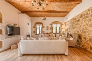una sala de estar con muebles blancos y una pared de piedra. en Pool Villa Michail, in Kissamos!, en Koukounará