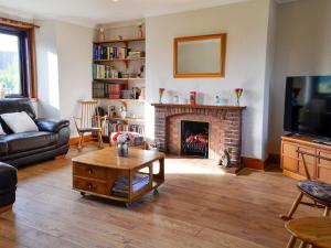uma sala de estar com lareira e televisão em The Smithy Of Longcastle em Whauphill