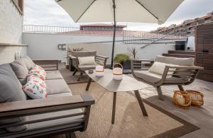 un patio con sofá, sillas y sombrilla en BARCELONA TOUCH APARTMENTS - Rosich, en Hospitalet de Llobregat