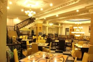 a restaurant with tables and chairs and a staircase at The Grand Palace Hotel Malang in Malang