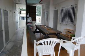 a dining room with a wooden table and white chairs at Guesthouse Iyonchi in Zamami