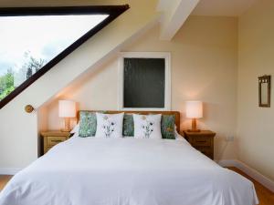 a bedroom with a white bed with two lamps at Pussywillow Cottage in Arlecdon