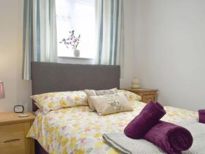 ein Schlafzimmer mit einem Bett mit lila Kissen und einem Fenster in der Unterkunft The Milk Place in Harby