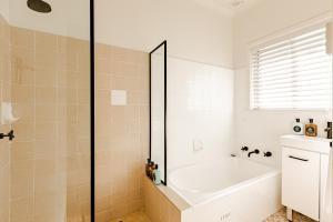 a white bathroom with a tub and a shower at Bay Breeze Boutique Accommodation in Batemans Bay