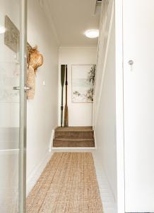 un pasillo con paredes blancas y una escalera con alfombra en Bay Breeze Boutique Accommodation, en Batemans Bay