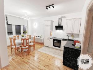 - une cuisine avec des placards blancs, une table et des chaises dans l'établissement Apartament Tuwim, à Przemyśl