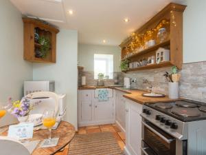 a kitchen with white cabinets and a stove top oven at Hippos Rest in Mow Cop