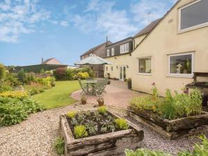 un jardín con mesa y sillas y una casa en Hippos Rest, en Mow Cop