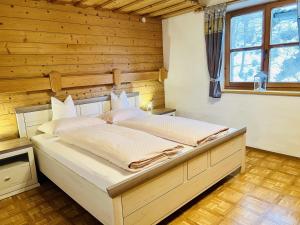 1 dormitorio con 1 cama grande en una pared de madera en Beim Talschuster, en Scheffau am Wilden Kaiser