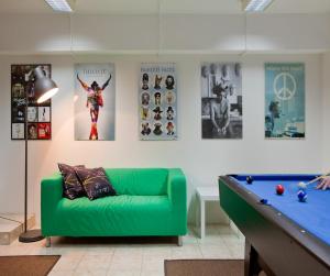 a living room with a green couch and a pool table at Hostel Bureau in Zagreb