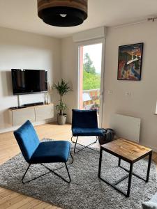 2 sillas azules y una mesa en la sala de estar en Gîte Ô Gré des Vosges 5 Étoiles Oberbronn, Vosges du Nord, en Oberbronn