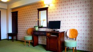 a room with a desk with a television and two chairs at Hotel Residenz in Suceava