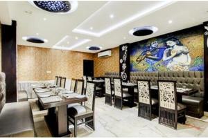 a restaurant with tables and chairs and a painting on the wall at Hotel The Idea Inn in Agra