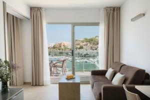 a living room with a couch and a large window at Porto Drach Aparthotel & Suites in Porto Cristo