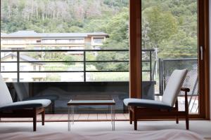 a room with two chairs and a table and a large window at Matsumoto Jujo in Matsumoto